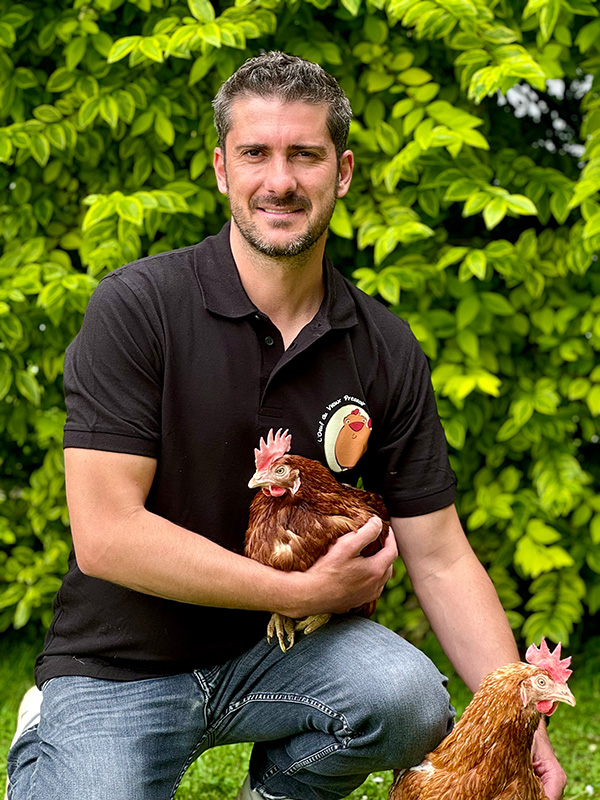 Éleveur tenant une poule en plein air chez L’Œuf du Vieux Pressoir, producteur d’œufs en Normandie.